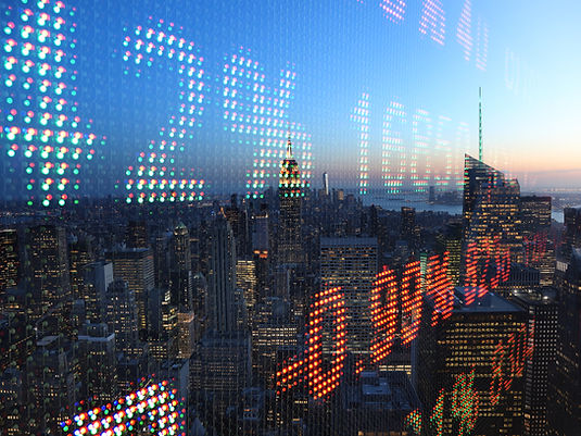 Dusk view of the New York City skyline seen through colorful LED reflections on glass, with the Empire State Building centered.